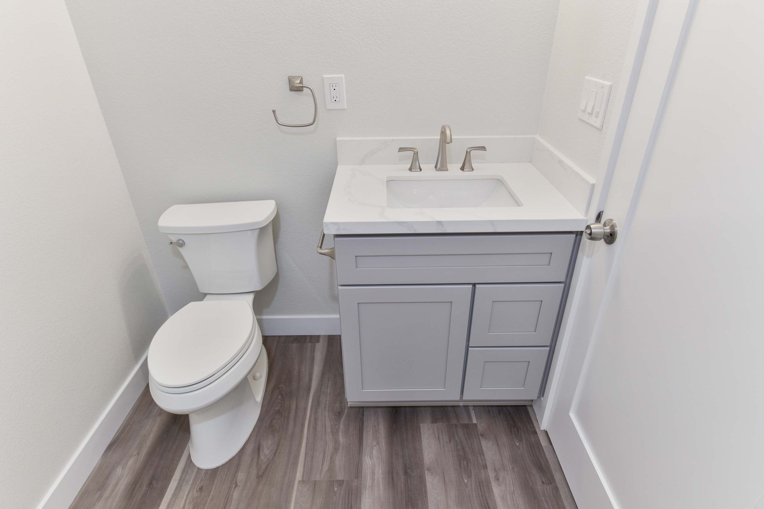 Updated bathroom vanity with quartz countertop, modern faucet, and durable luxury vinyl plank flooring installed as part of this full home renovation.