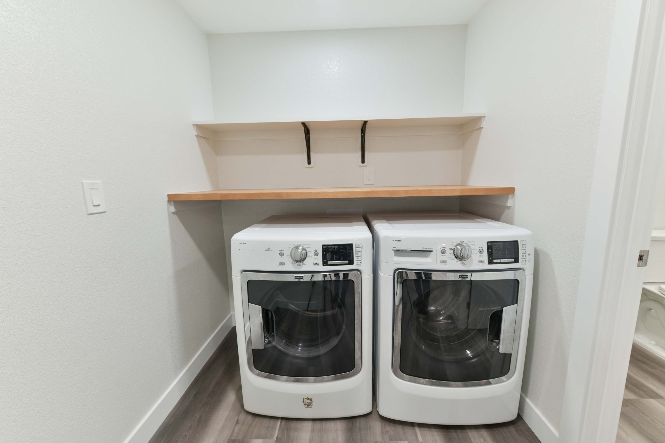 New laundry room with side-by-side washer and dryer, built-in shelving, durable flooring, and clean, functional finishes.