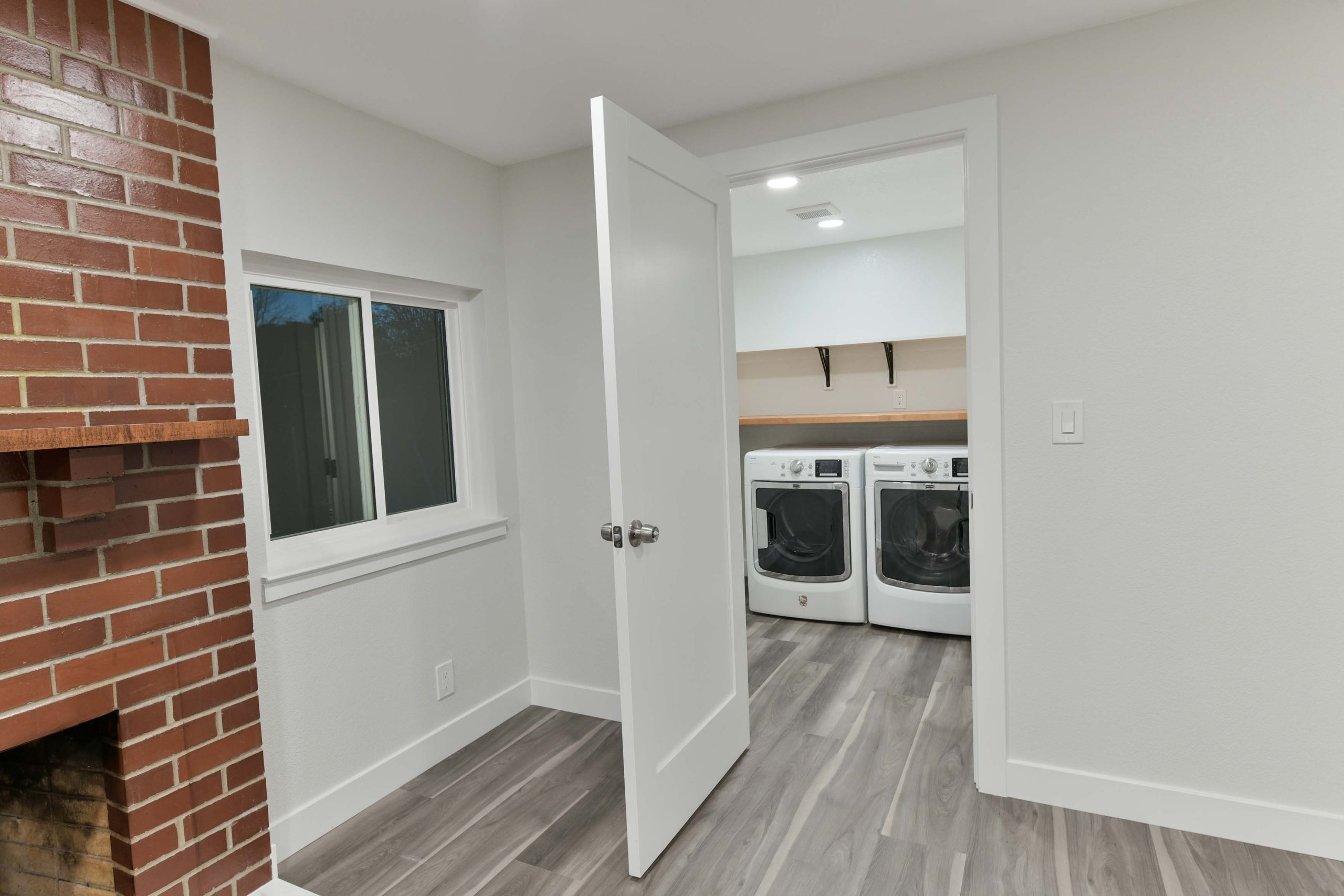 Living area renovation showing new flooring, recessed lighting, and direct access to a newly added laundry room as part of the whole house update.