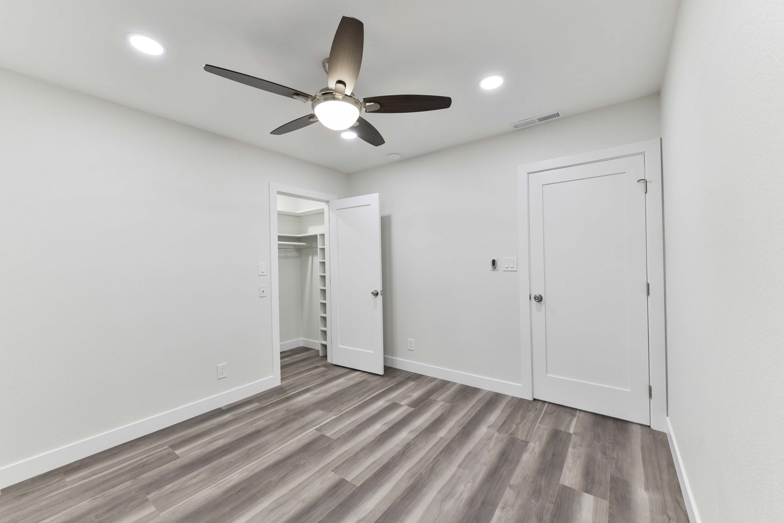 Renovated bedroom with new flooring, fresh paint, modern lighting, and clean trim details completed as part of the whole house renovation.