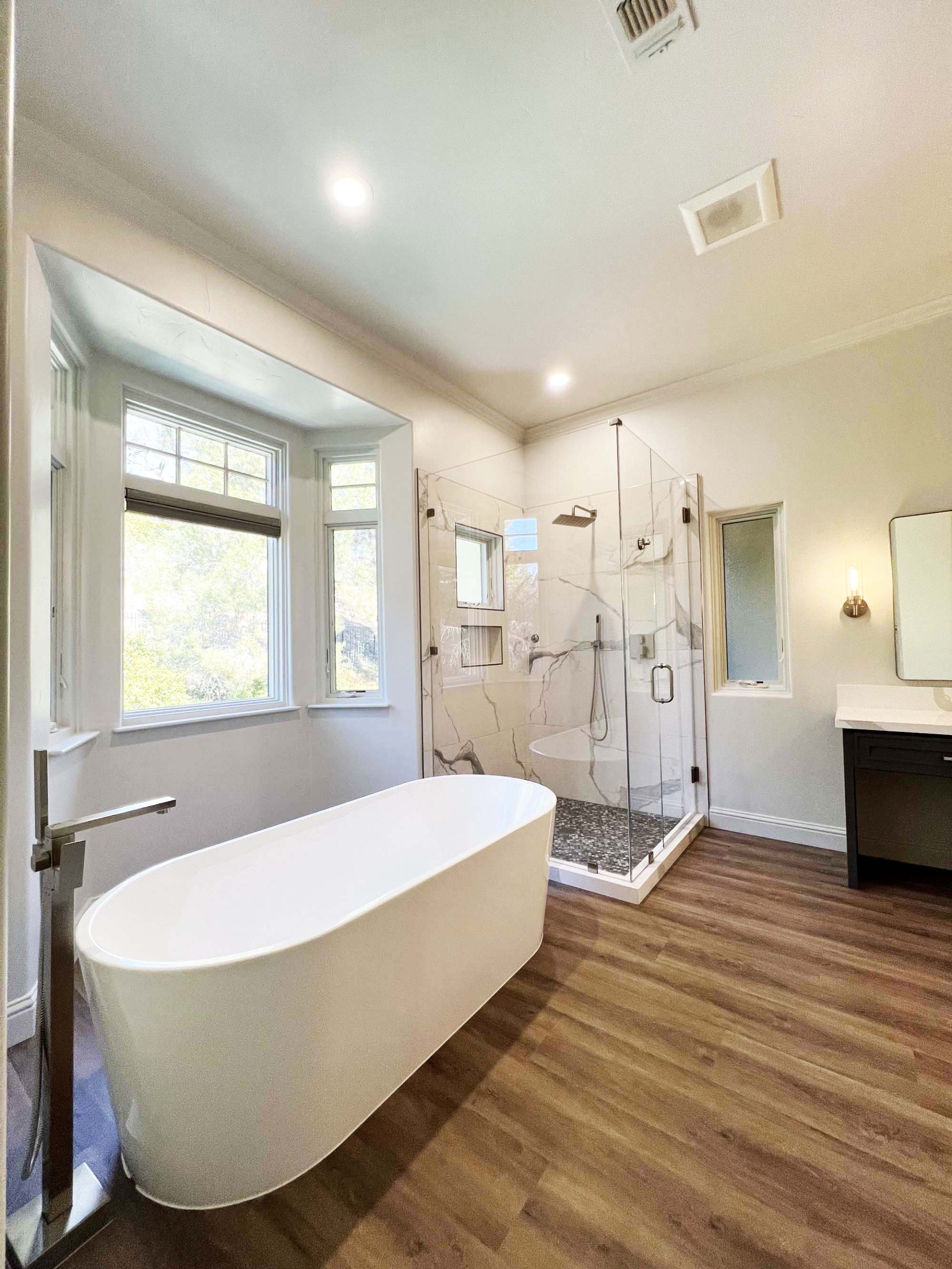 Freestanding soaking tub and glass-enclosed walk-in shower in a master bathroom remodel in Granite Bay, CA 95746