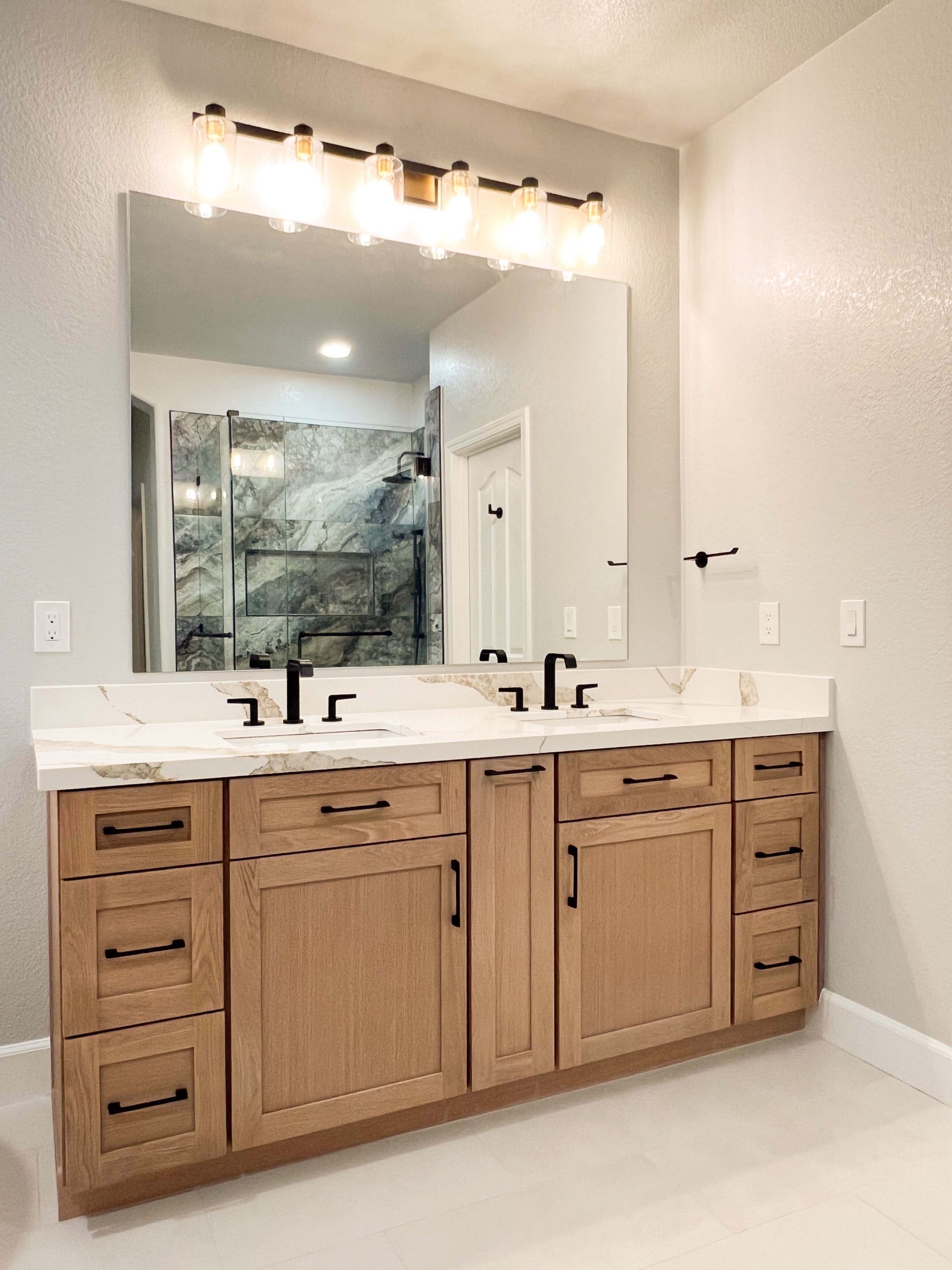 Custom double-sink vanity with quartz countertop and warm wood cabinetry in a fully remodeled second-floor bathroom in Roseville, CA.