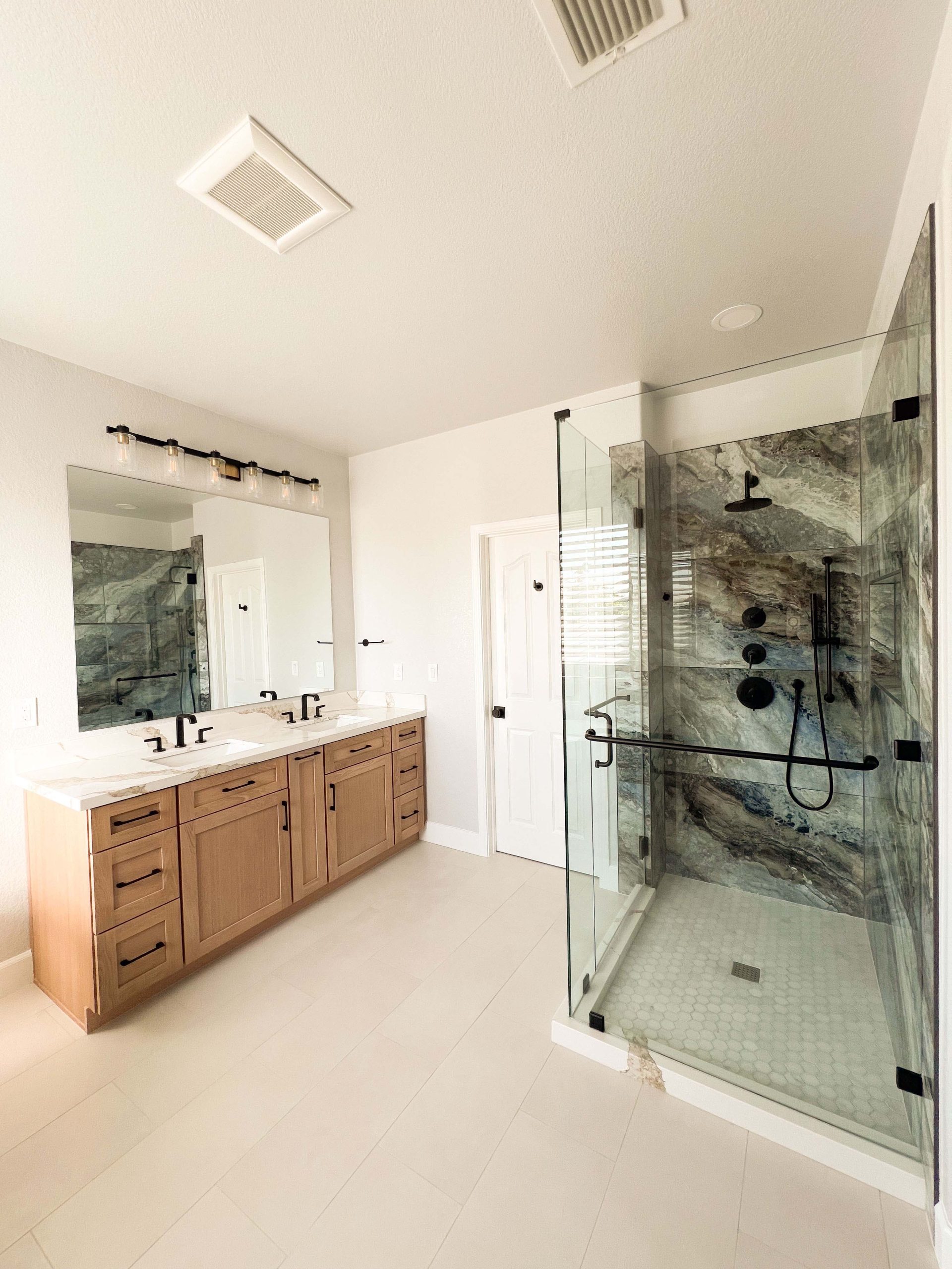 Second-floor bathroom remodel in Roseville featuring an expanded walk-in shower, glass enclosure, and custom double vanity after full demolition and layout changes.