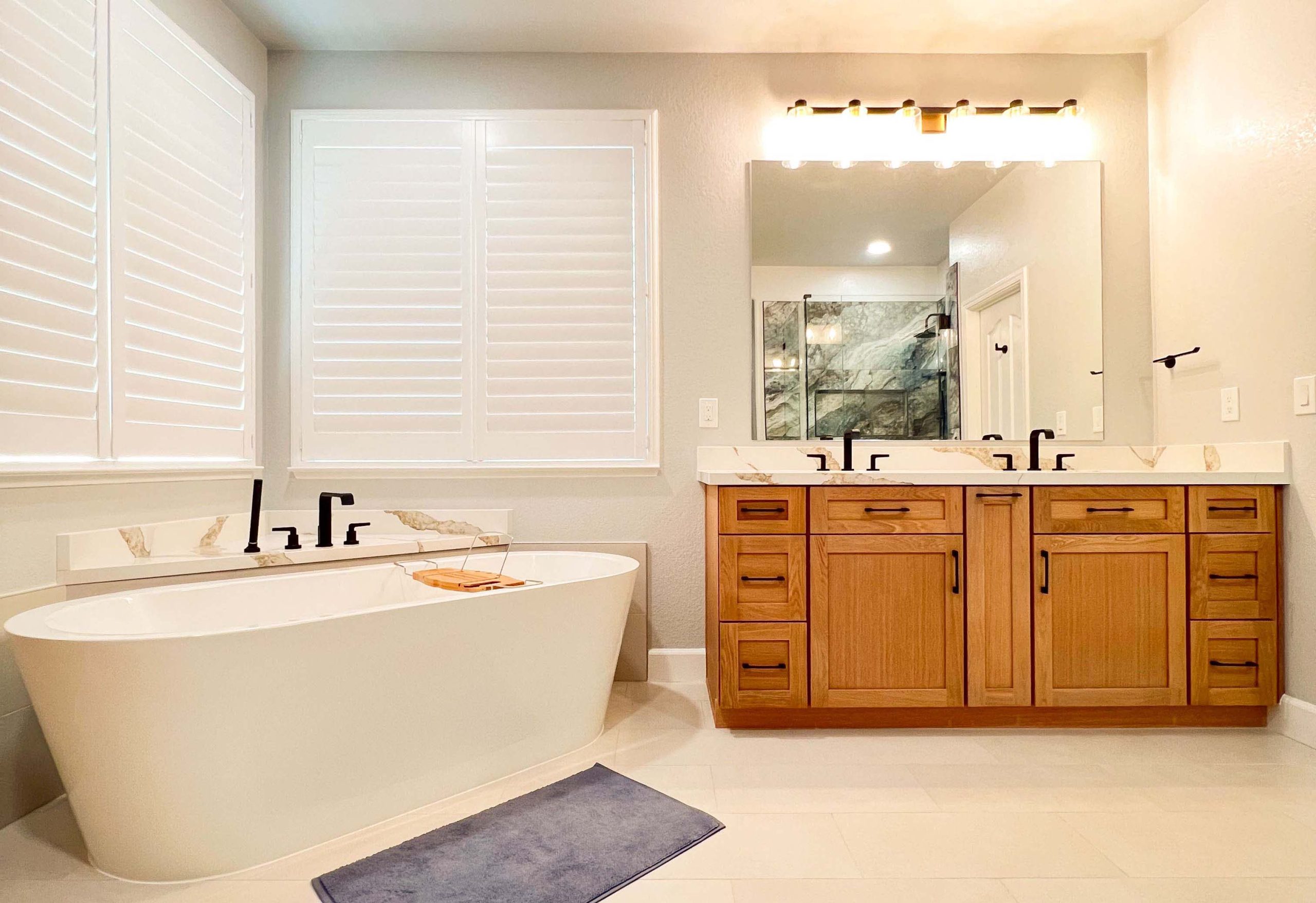 Freestanding soaking tub positioned beneath plantation shutters as part of a full bathroom remodel in Roseville, California.