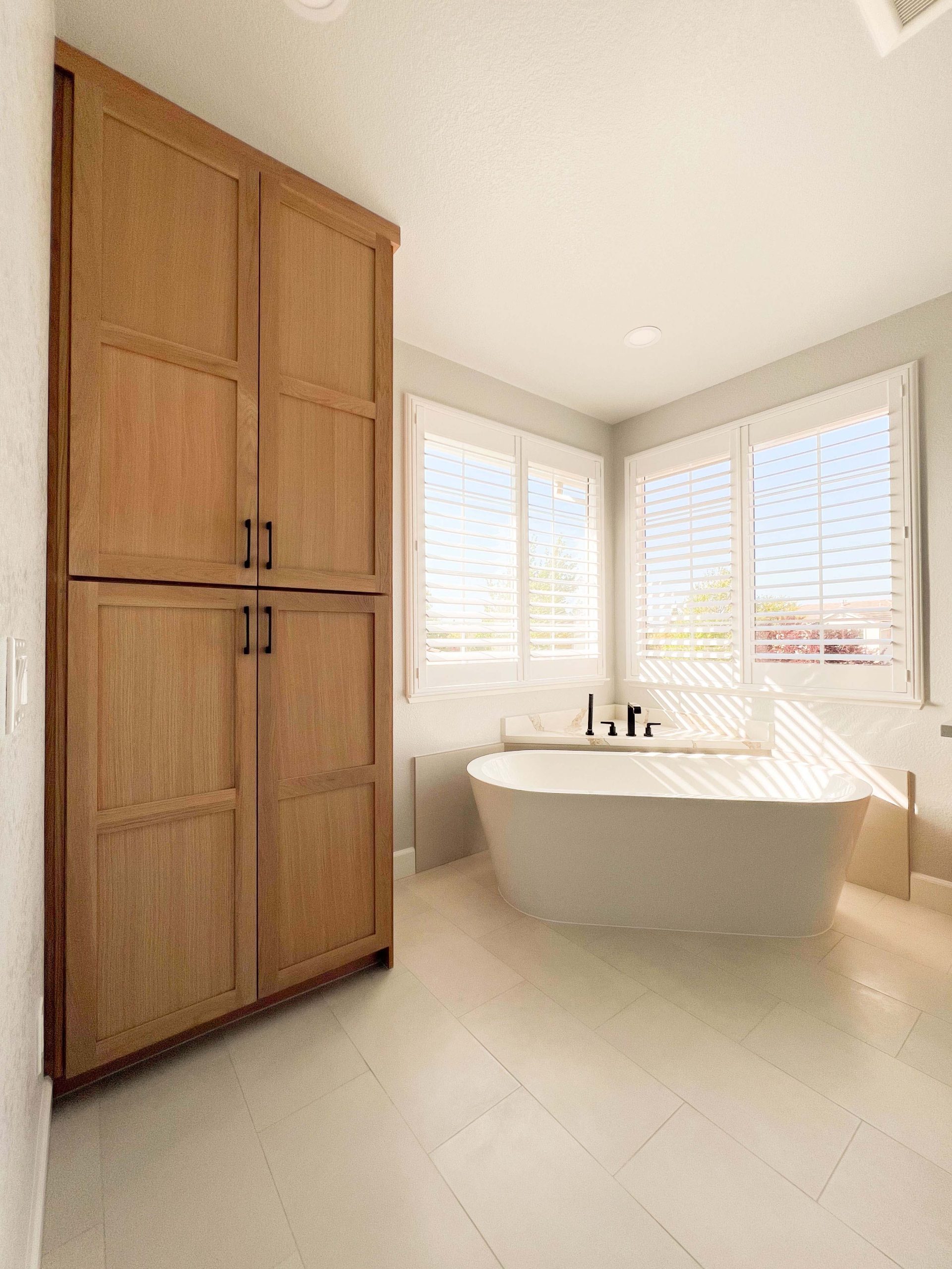 Bathroom remodel in Roseville, CA featuring a freestanding tub, added pantry-style storage cabinets, and relocated plumbing for improved function and flow.