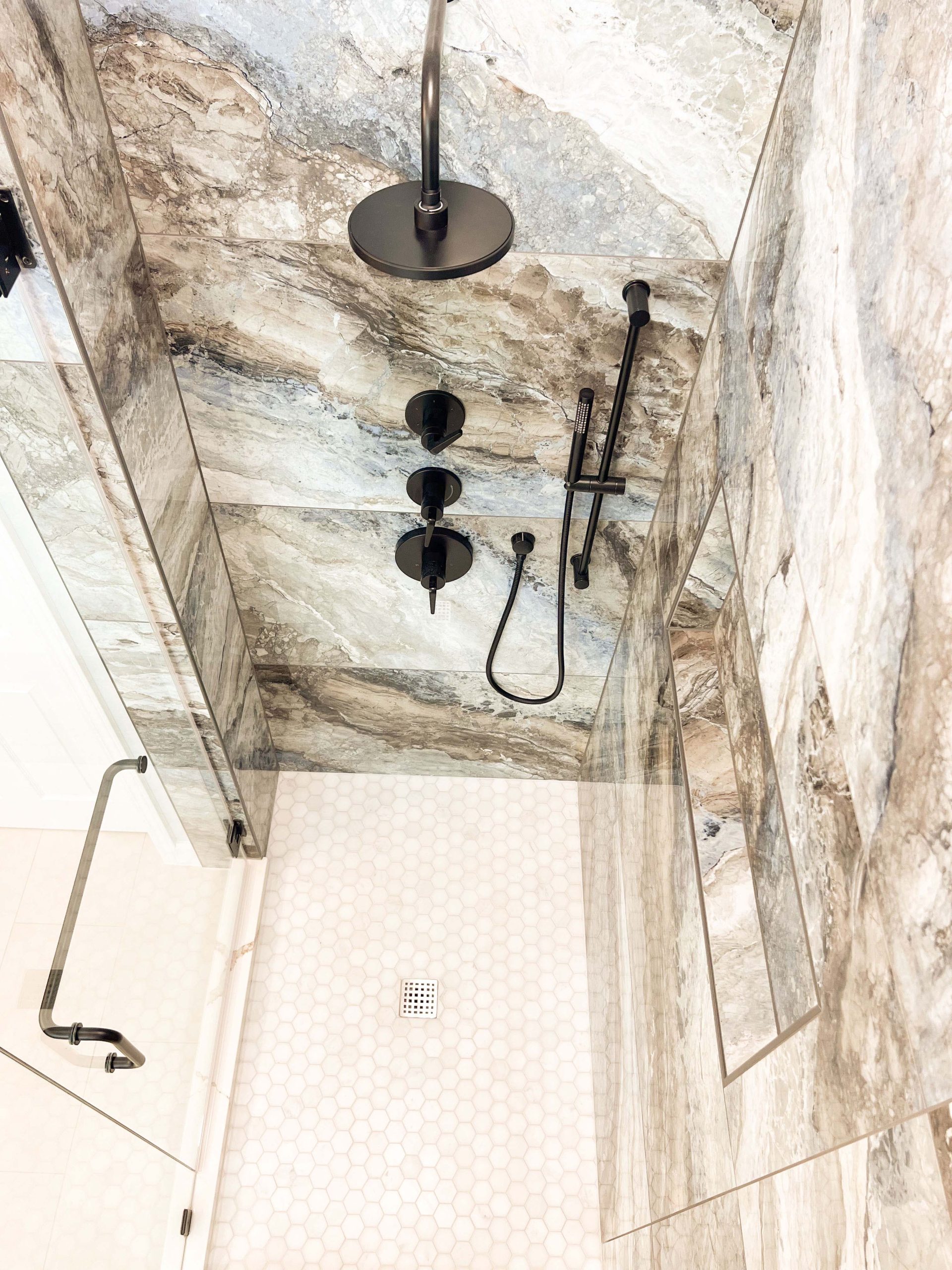 Custom walk-in shower with large-format stone-look tile, matte black fixtures, and hex tile flooring in a Roseville bathroom remodel.