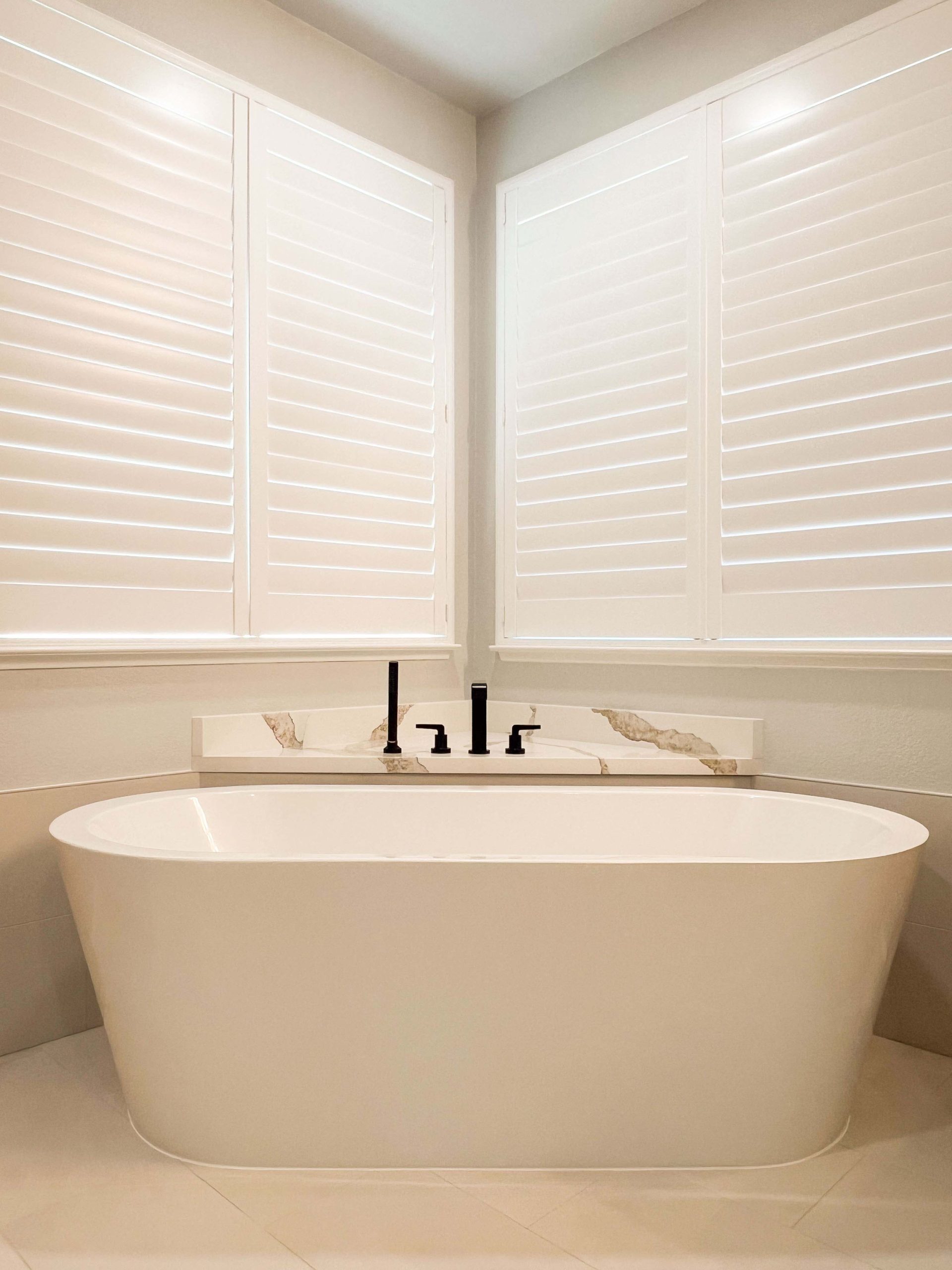 Modern master bathroom remodel in Roseville featuring a sleek freestanding tub with relocated plumbing and custom stone backsplash.