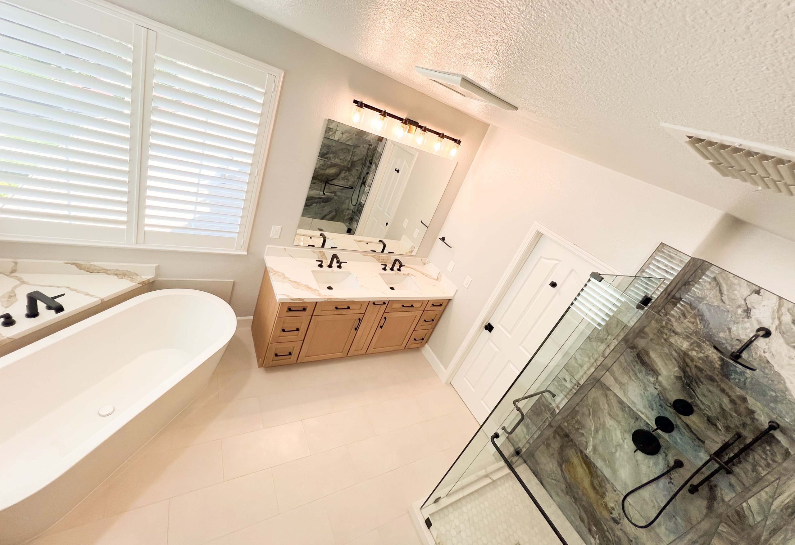 Wide layout of a master bathroom remodel in Roseville showcasing the freestanding tub, double-sink vanity, and expanded walk-in shower.