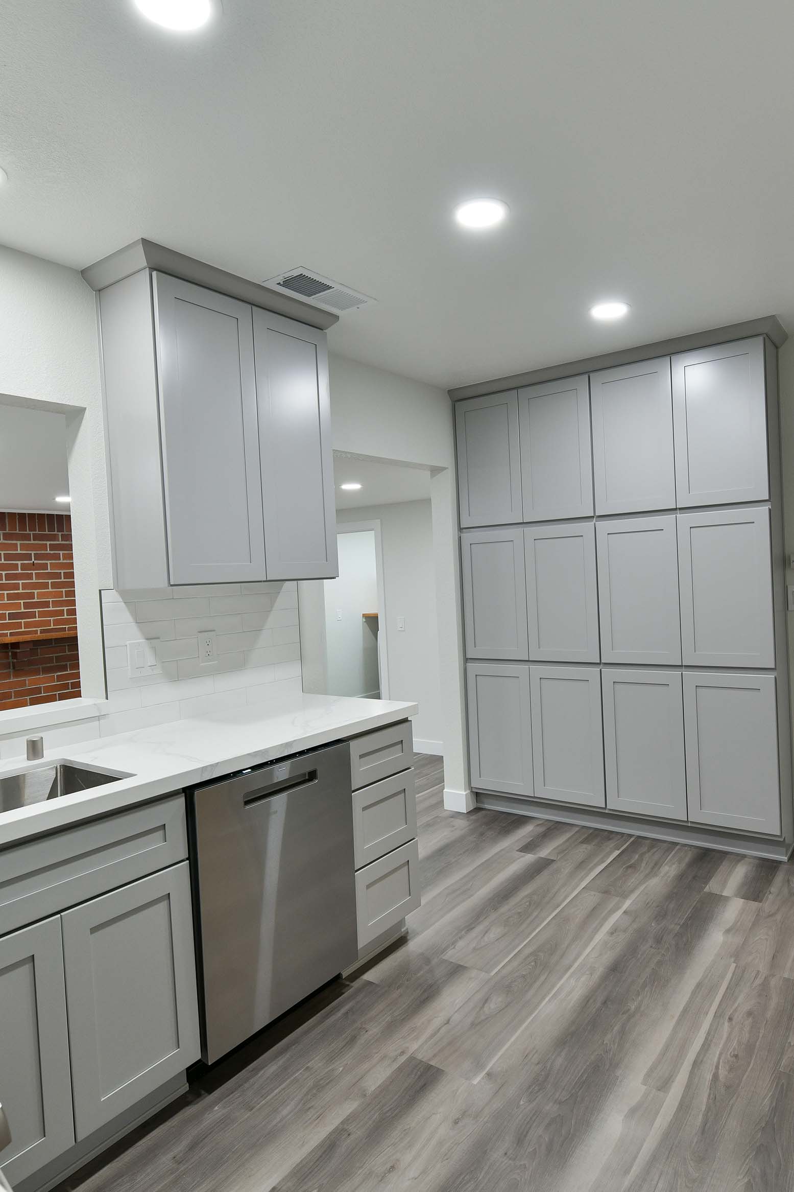Kitchen storage wall with custom cabinetry, integrated appliances, and durable flooring.