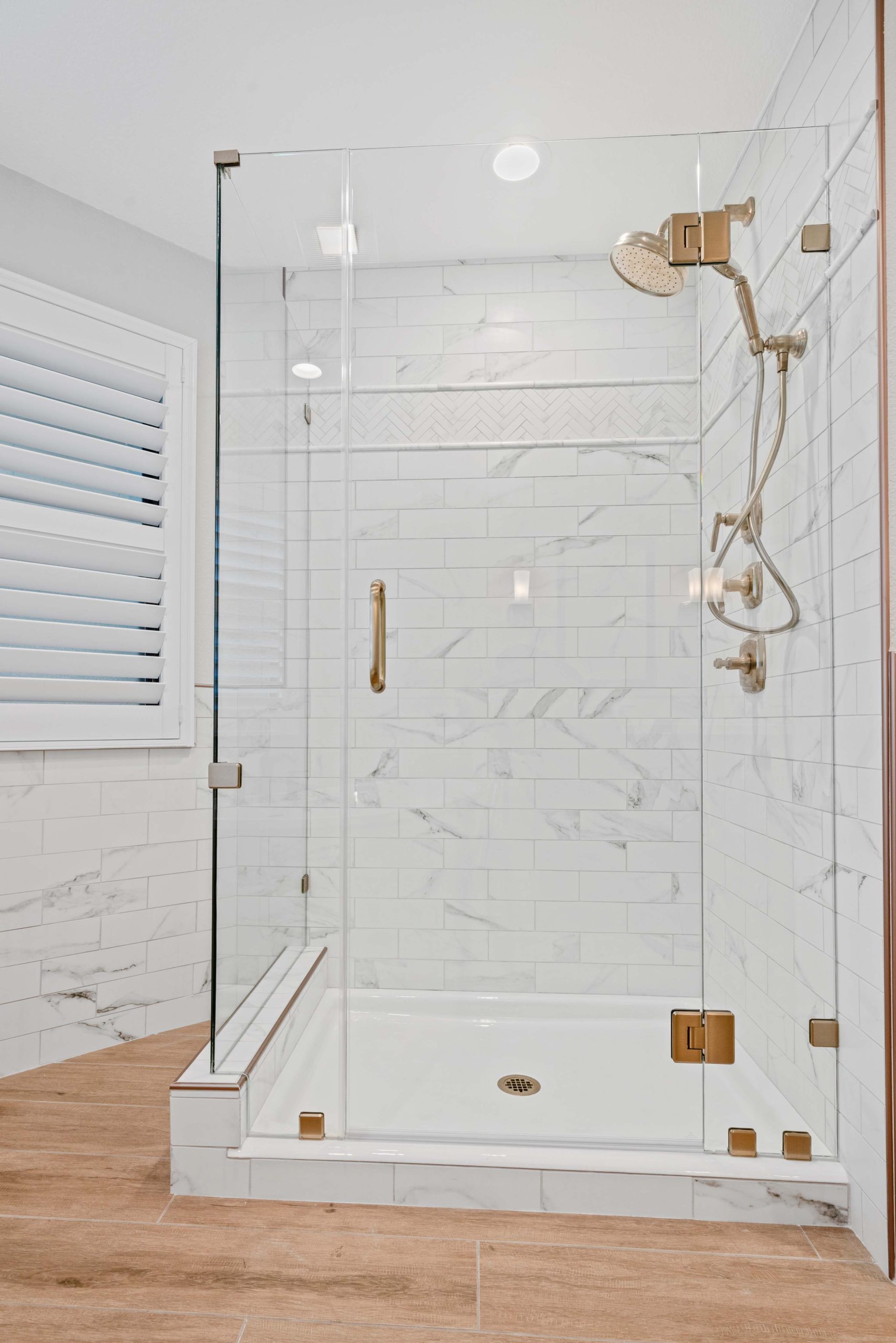 Frameless glass shower installed as part of a master bathroom remodel in Sacramento, CA 95825, featuring marble-look tile walls, bronze fixtures, and a clean, modern layout.