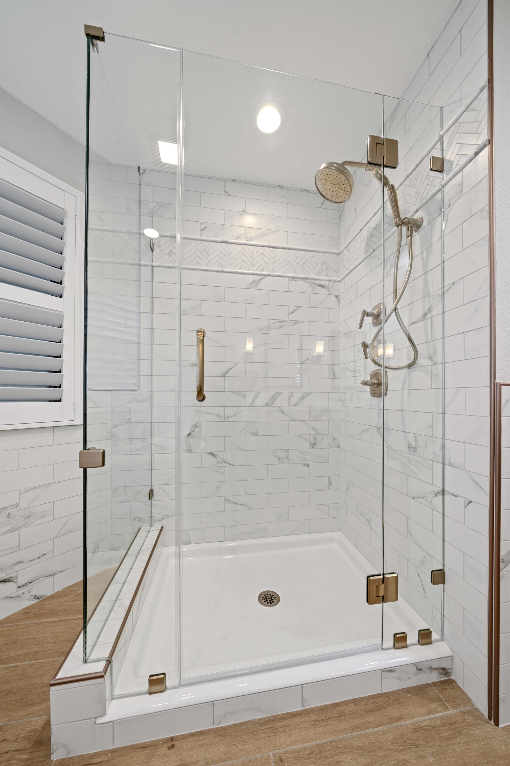 Walk-in shower detail from a Sacramento master bathroom remodel, showcasing full-height tile, brushed bronze hardware, and improved lighting for a brighter, more open feel.