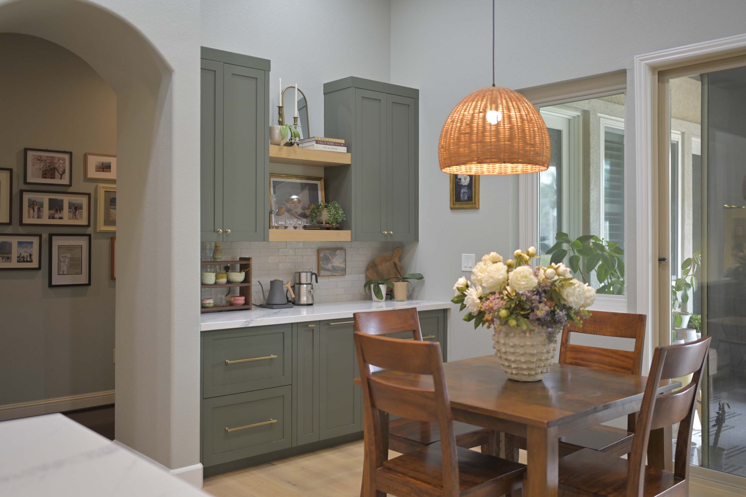 Kitchen remodel in Elk Grove, CA 95758 showcasing a built in coffee bar, green cabinetry, open shelving, and an adjacent dining area with warm natural finishes.