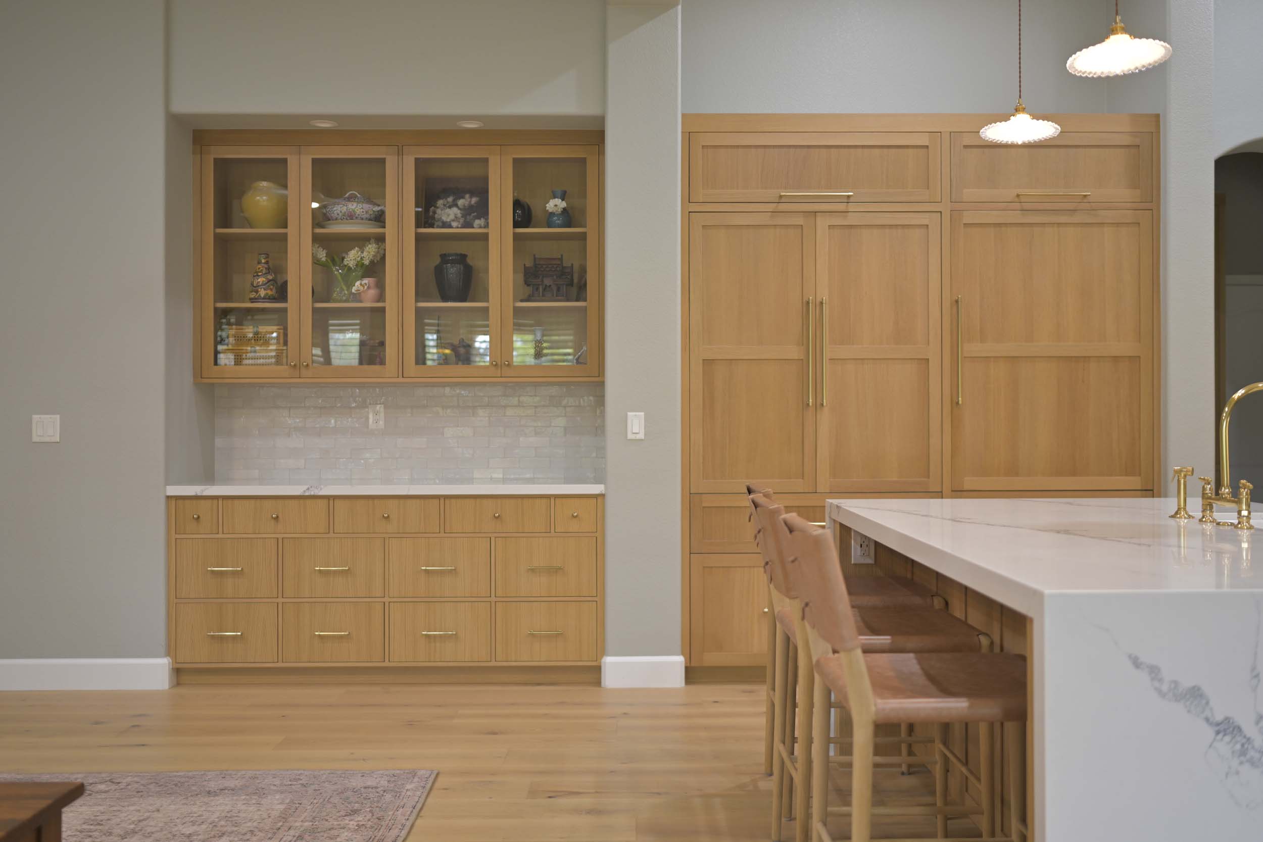 Kitchen remodel in Elk Grove, CA 95758 featuring glass front cabinets, custom pantry storage, warm wood cabinetry, and a white waterfall island.
