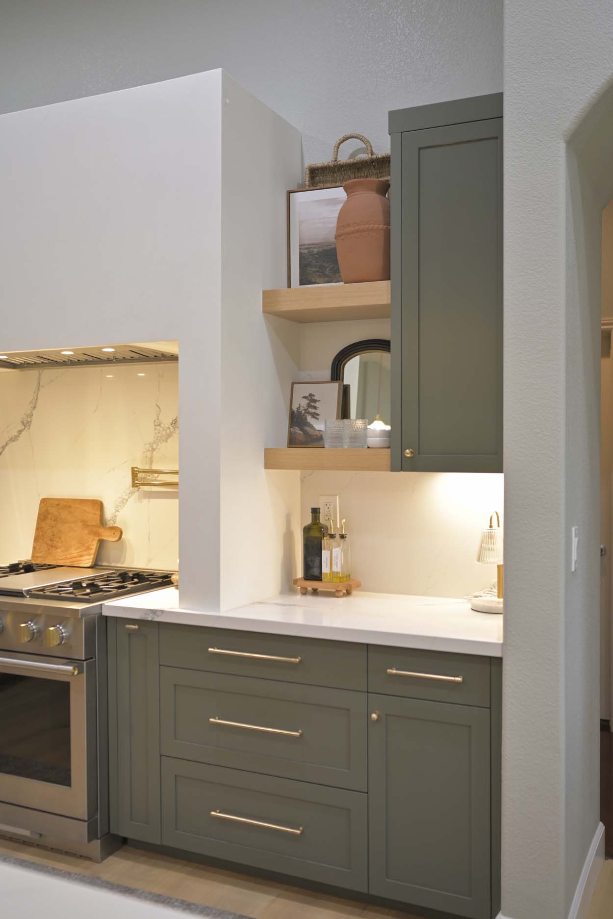 Kitchen remodel in Elk Grove, CA 95758 with green shaker cabinets, open wood shelving, white countertops, and a custom plaster range hood.
