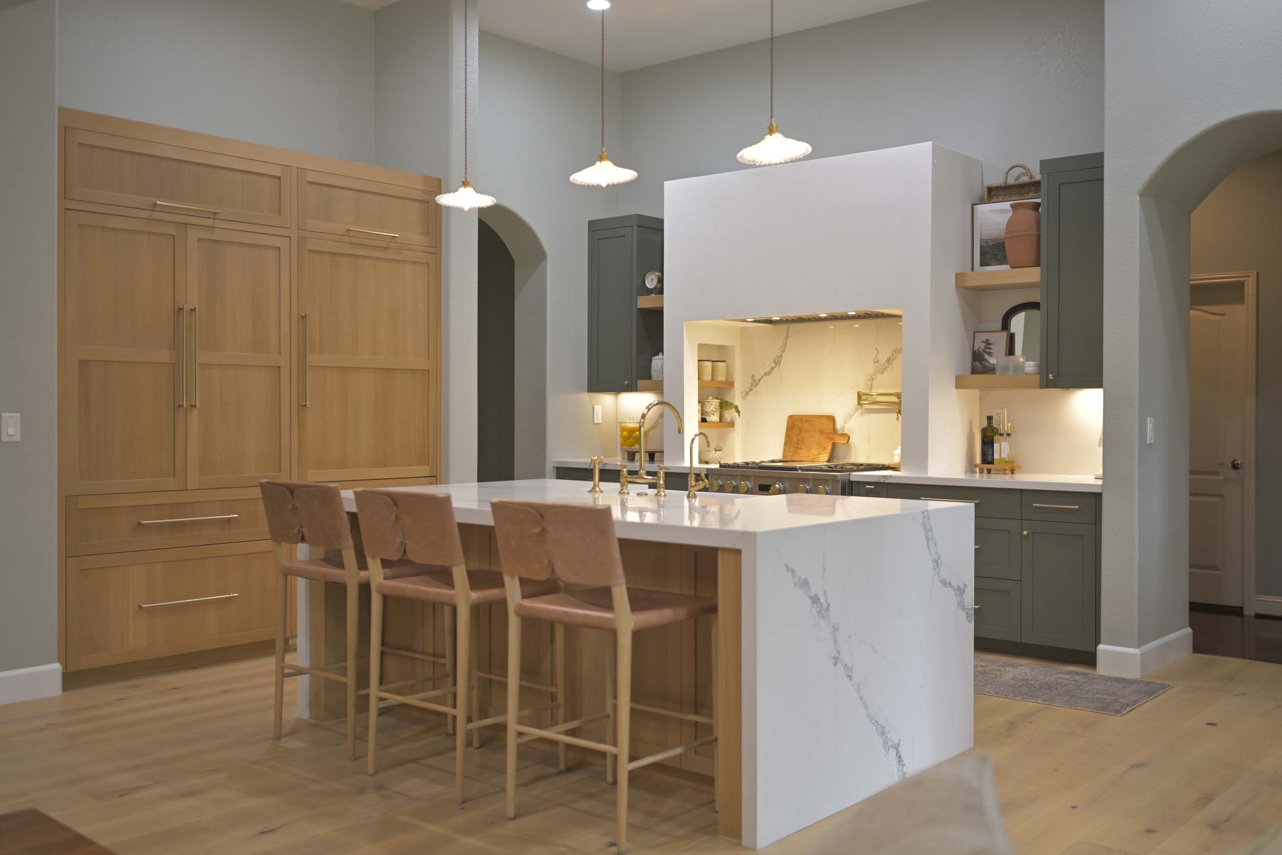 Kitchen remodel in Elk Grove, CA 95758 featuring a white waterfall island, custom wood cabinetry, green perimeter cabinets, and a statement plaster range hood.