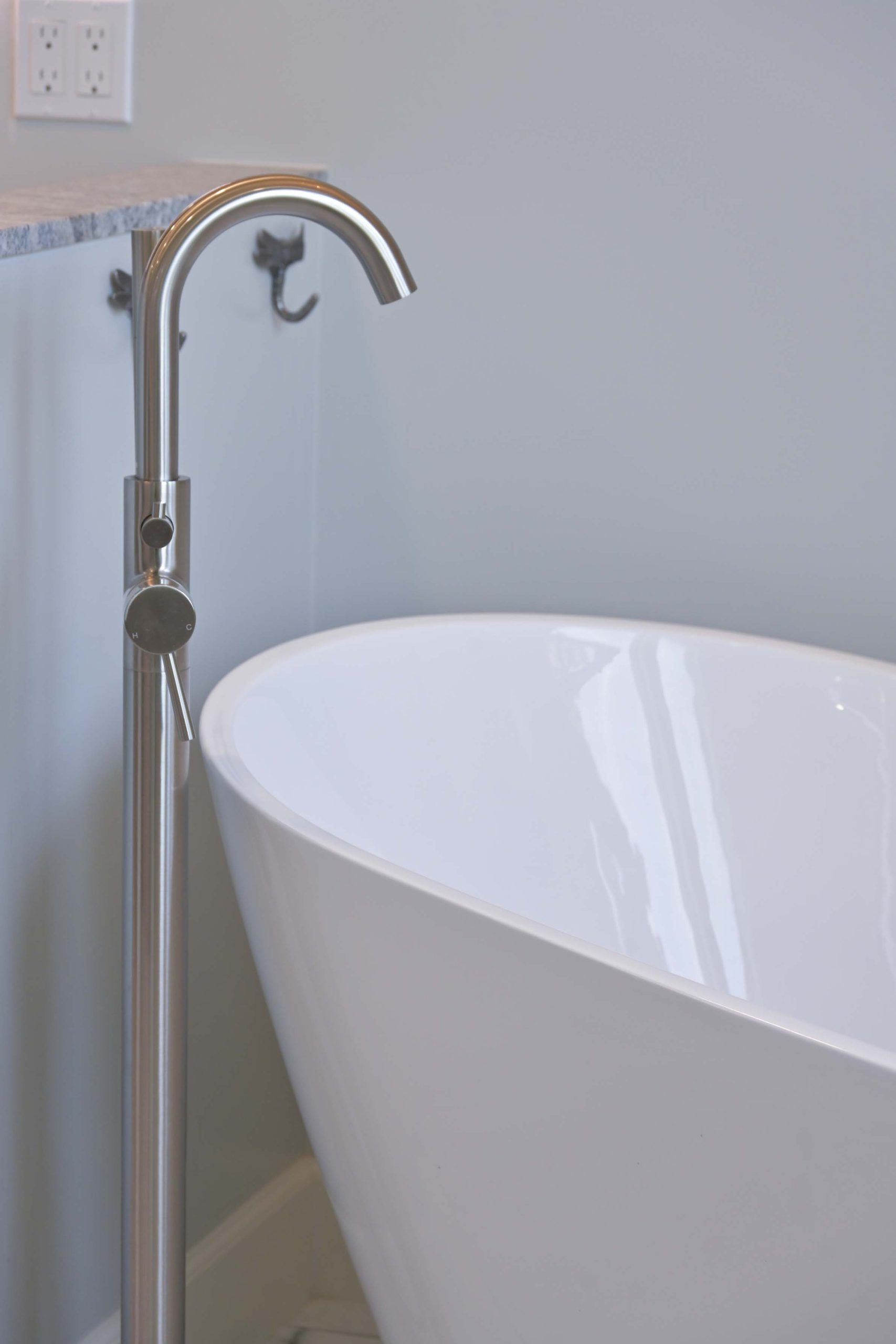 Brushed nickel floor mounted tub filler next to a freestanding soaking tub in Rocklin, CA 95765