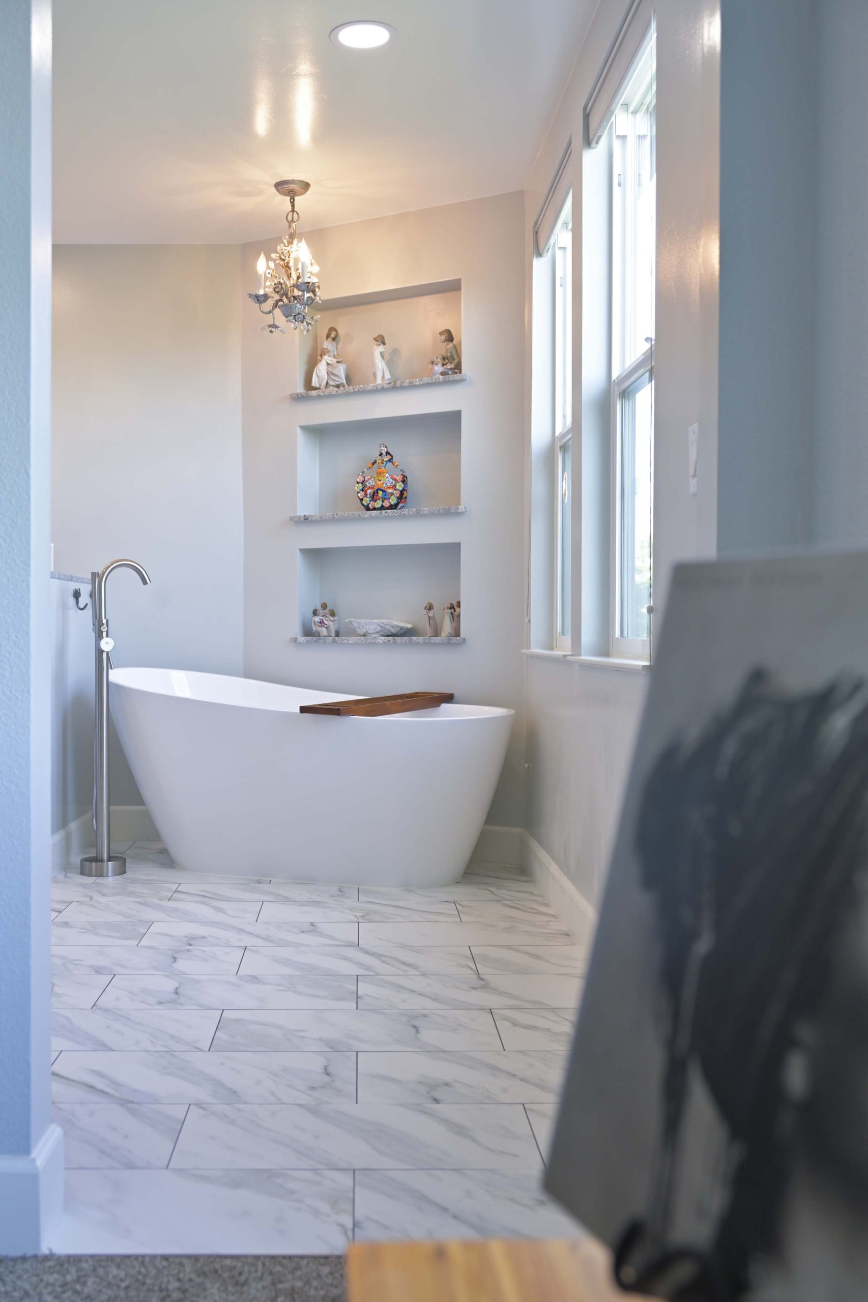 Freestanding tub with built in wall shelves and tall windows in a master bathroom remodel in Rocklin, CA 95765