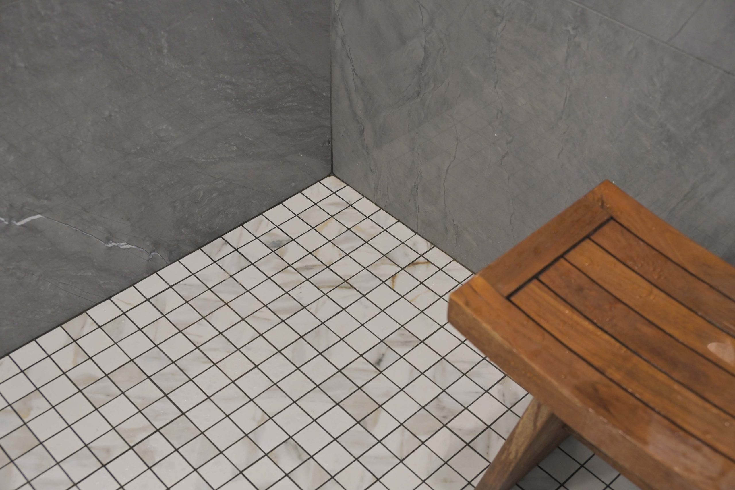 White mosaic shower floor with wood bench in a master bathroom remodel in Rocklin, CA 95765