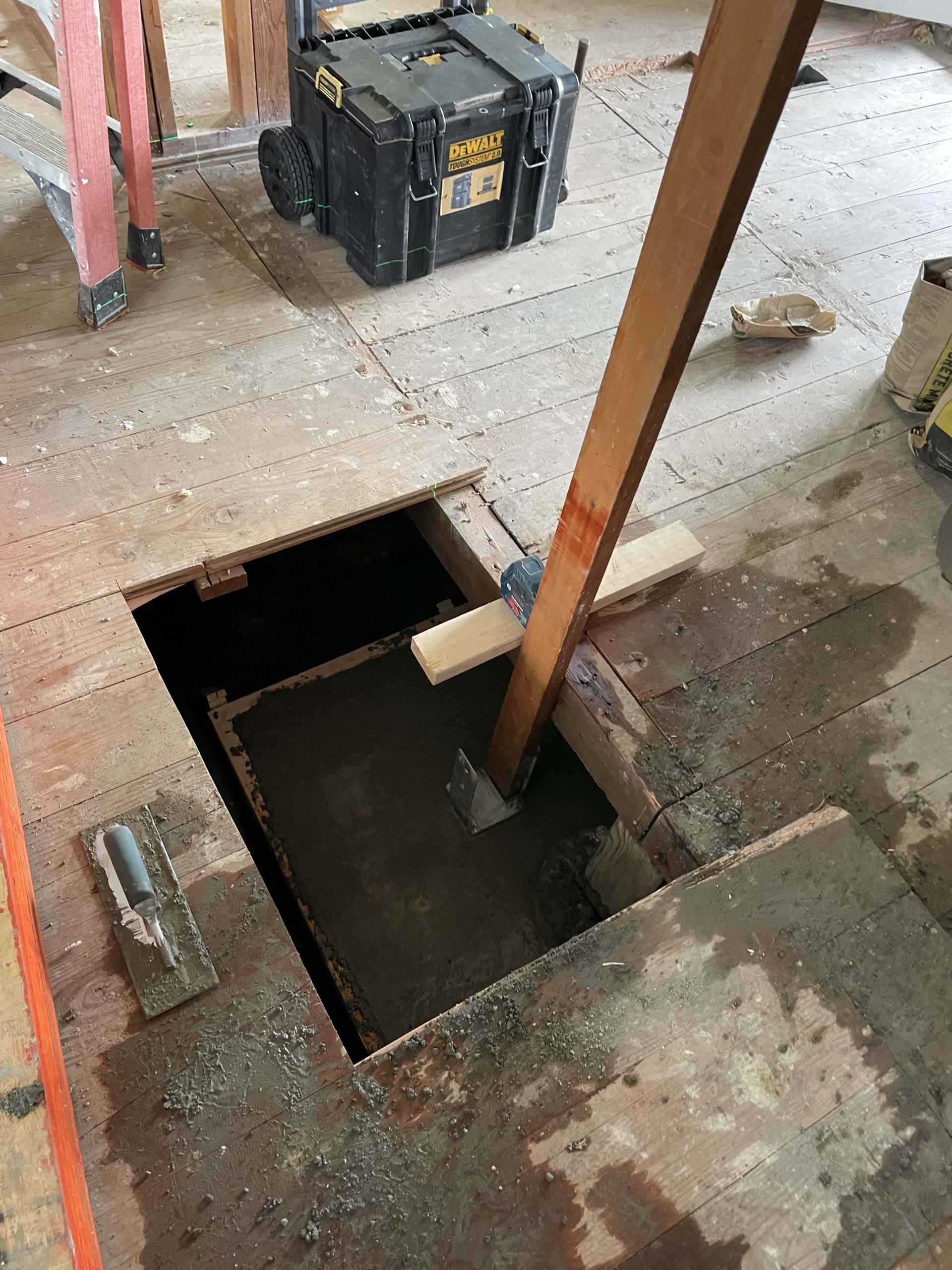 Concrete pour for the new structural support pier with temporary post in place during the open-concept kitchen transformation